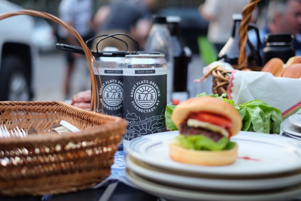 Two Great Flats branded beer cans sit on top of a picnic spread on a Summer day