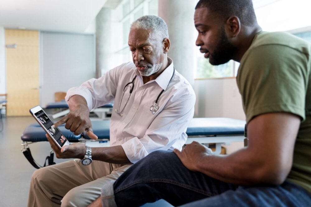 A doctor showing a patient his results on a mobile device running VisualDx