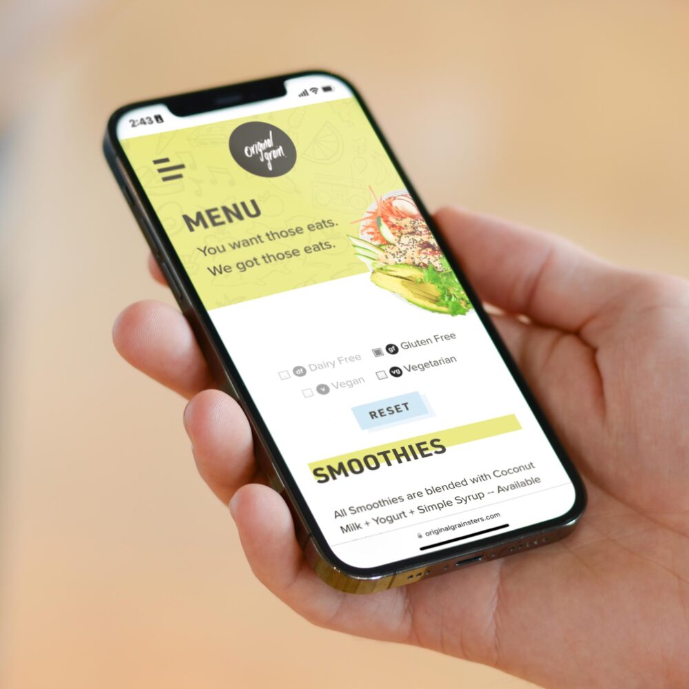 Original Grain's responsive and dynamic dining menu displayed on an iPhone 12 held by a customer